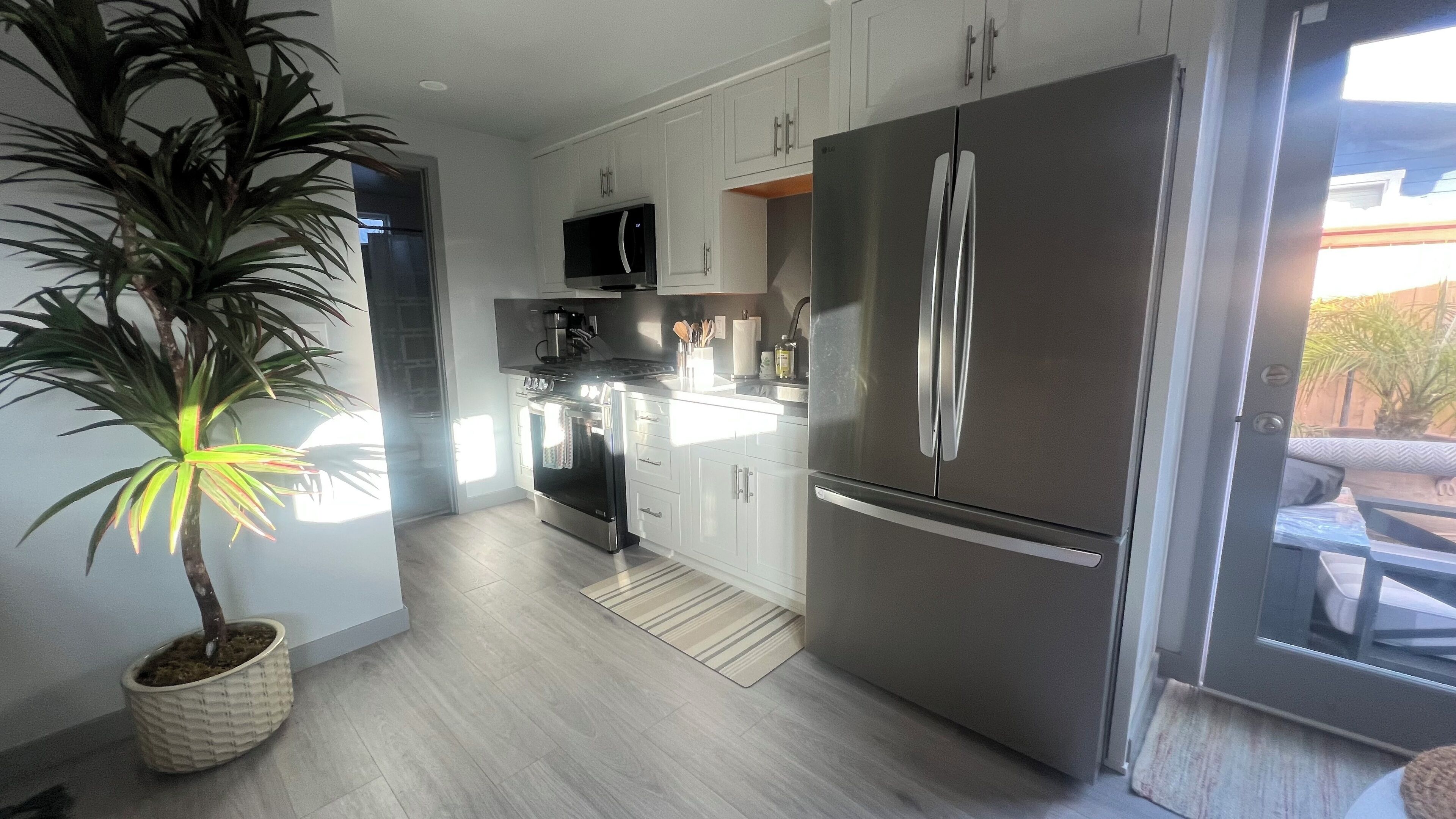 A modern kitchen with stainless steel appliances, white cabinetry, and a potted plant.