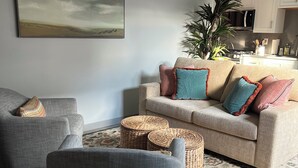 A living room with a sofa, armchairs, a coffee table, a patterned rug, and a painting on the wall. - Charming 1-bedroom townhome in brilliant Hermosa Beach (Hermosa Beach)
