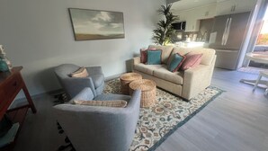 A living room with a sofa, armchair, and a small table. There is a kitchen in the background with a refrigerator and a microwave. - Charming 1-bedroom townhome in brilliant Hermosa Beach (Hermosa Beach)
