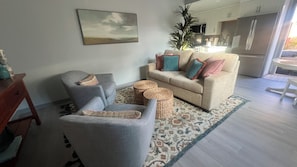 A living room with a sofa, armchair, and a small table. There is a kitchen in the background with a refrigerator and a microwave. - Charming 1-bedroom townhome in brilliant Hermosa Beach (Hermosa Beach)