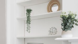 Un interno luminoso con un divano blu scuro, una lampada ed elementi decorativi su mensole.
