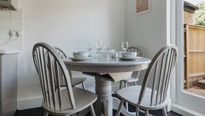 Un tavolo da pranzo con quattro sedie, una parete bianca e un quadro incorniciato.