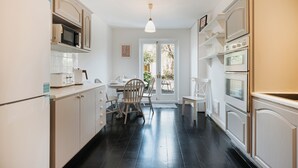 Una cucina con mobili bianchi, un forno a microonde, un tostapane e un'area pranzo con sedie e un tavolo.
