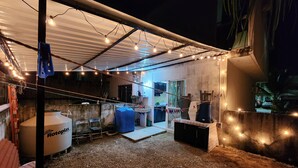 A covered outdoor area with a kitchen, chairs, and a large water tank. - Residencia Mejía · Descanso y Comodidad a Minutos del Mar Caribe (Playa del Carmen)
