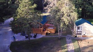 Une cabane dotée d’une terrasse en bois, d’un petit abri de jardin et d’une maison avec un toit végétalisé.