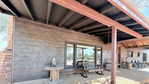 A covered outdoor area with wooden walls, a bench, and a table with a decorative item.