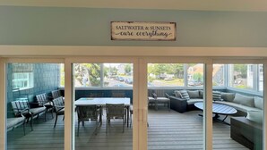 Un espacio cubierto con patio, una mesa, sillas, un sofá y un cartel arriba.