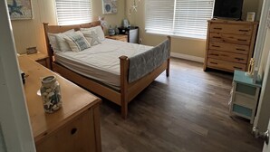 Un dormitorio con cama de madera, mesita de noche, cómoda y ventilador de techo.