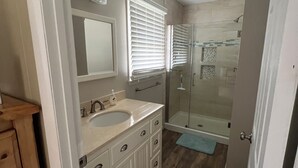 Un baño con tocador doble, cabina de ducha de vidrio y ducha a ras de suelo.