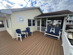 A covered deck with wooden flooring and outdoor seating.