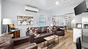 A modern living room with leather sofas, a coffee table, and artwork on the walls. - The Horseshoe Hideaway - Rodeo Themed & 1/2 mile walk to Whiskey Row! (Prescott)