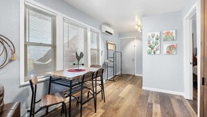 A dining area with a wooden table and chairs, a red placemat, and a wall-mounted rack with clothes. - The Horseshoe Hideaway - Rodeo Themed & 1/2 mile walk to Whiskey Row! (Prescott)