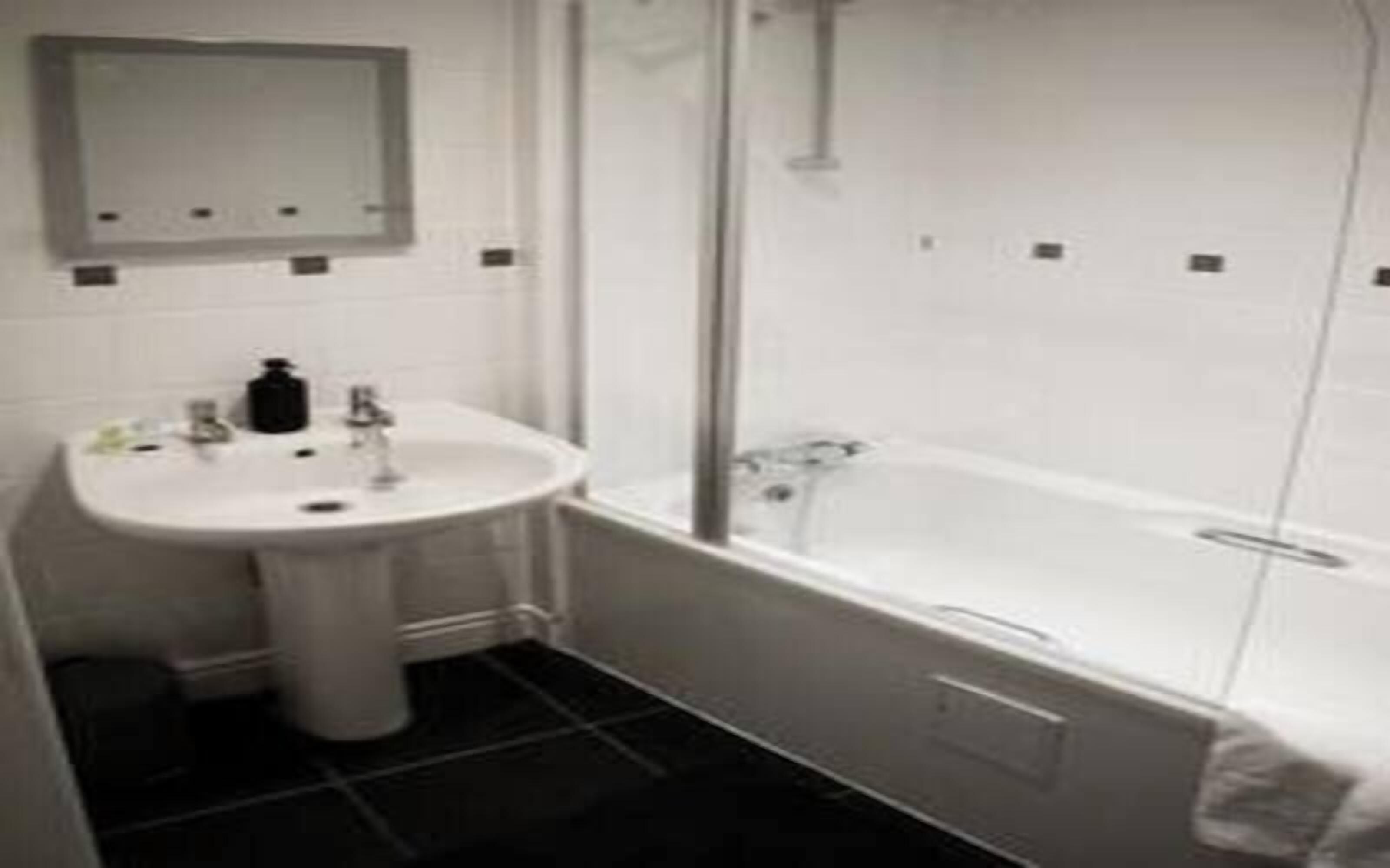 A bathroom with a white sink, mirror, and bathtub.