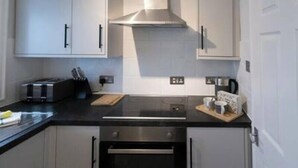 Eine moderne Küche mit weißen Schränken, einer schwarzen Arbeitsplatte, einem eingebauten Backofen und einer Edelstahl-Dunstabzugshaube.