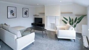 Ein modernes Wohnzimmer mit einer Couch, einem Couchtisch und einem Fernseher. An der Wand befinden sich zwei gerahmte Bilder.