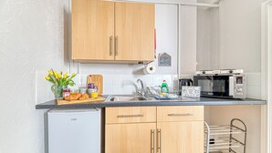 A kitchen with wooden cabinets, a microwave, a sink, and a small refrigerator.