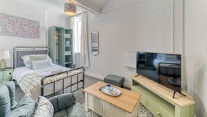 A bedroom with a bed, bedside table, TV, and a green cabinet.