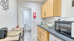 Eine Küche mit Holzausstattung, einer Mikrowelle, einem Toaster und einem Spülbecken.