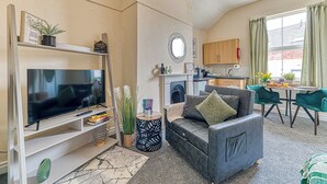 A living room with a TV, sofa, and a dining area with chairs.