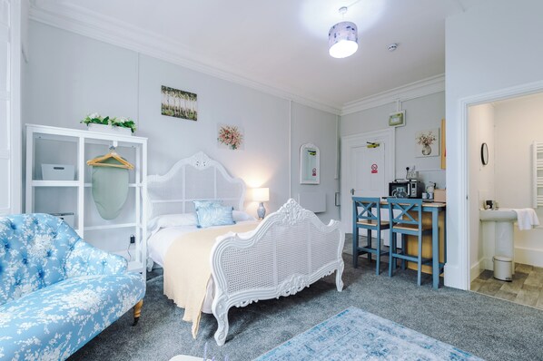 Une chambre à coucher comprenant un lit, une commode, une chaise et un bureau avec une autre chaise.