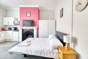 Un dormitorio con cama, mesita de noche y un reloj en la pared.