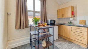 Una cocina con una mesa, un microondas, un tostador y un lavamanos.