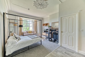 A bedroom with a four-poster bed, a sofa, a desk, and a chair.
