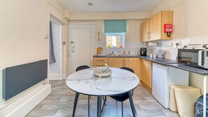 A compact kitchen with a round marble table, wooden cabinets, a microwave, and a fire extinguisher. - Chester Heights by Guestz (Chester)