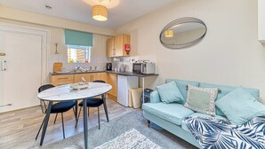 A compact living space with a kitchenette, dining area, and a sofa with patterned cushions. - Chester Heights by Guestz (Chester)