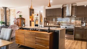 A modern kitchen with a central island, stainless steel appliances, and wooden cabinetry. - Entertainer's paradise pool, Spa, Movie room pet friendly, close to Aust Zoo! (Queensland)
