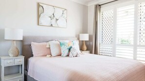 A bedroom with a bed, two bedside tables, a lamp, a decorative wall piece, and a window with blinds. - Entertainer's paradise pool, Spa, Movie room pet friendly, close to Aust Zoo! (Queensland)