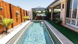 A rectangular swimming pool with a wooden fence on one side and a house on the other. - Entertainer's paradise pool, Spa, Movie room pet friendly, close to Aust Zoo! (Queensland)