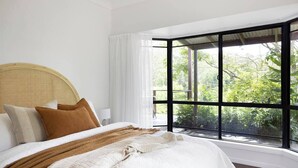 A bedroom with a large window, a wicker headboard, and a bed with multiple pillows and a blanket. - Luxury Hinterland Hideaway with Breathtaking Views (Queensland)