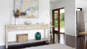 A modern kitchen with a wooden console table, a painting, and a view to the outdoors. - Luxury Hinterland Hideaway with Breathtaking Views (Queensland)