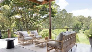 A covered outdoor seating area with wicker furniture and a view of the surrounding greenery. - Luxury Hinterland Hideaway with Breathtaking Views (Queensland)