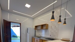 Une cuisine moderne dotée d’un îlot en granit, de luminaires suspendus et d’un réfrigérateur.