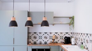 Una cocina moderna con luces colgantes, encimera de madera y salpicadero con diseño geométrico.