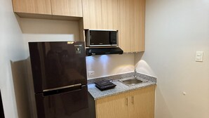 A compact kitchen with a black refrigerator, a microwave, and a granite countertop.
