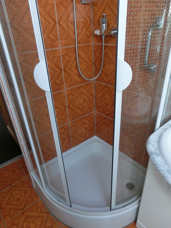 A shower enclosure with a white tub and a patterned tile wall.