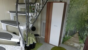 Una escalera con barandilla de metal, una puerta blanca y una zona alfombrada de color verde que conduce a una puerta.