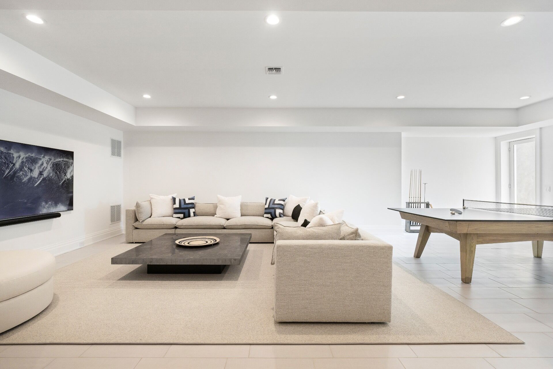 A modern living room with a sofa, coffee table, and a ping pong table.