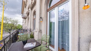 A balcony with a table, chairs, a potted plant, and a book.