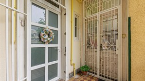 A door with a glass panel and a decorative wreath, a metal gate, and a tiled entrance area.