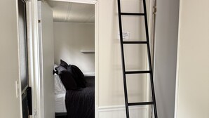 Un dormitorio con cama doble, una escalera y una puerta que da a otra habitación.