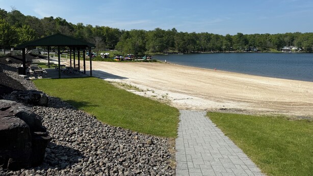 Una playa con un pabellón, mesas de picnic y un sendero pavimentado.