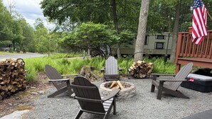 Un espacio al aire libre con sillas Adirondack, una chimenea y una pila de leña.