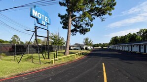 Un letrero de motel, una carretera con línea amarilla y una cerca con un árbol.