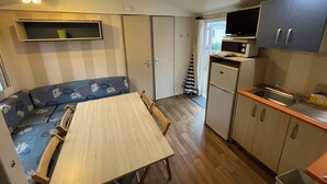 A compact kitchen with a dining table, a microwave, and a refrigerator. - 3-bedroom mobile home with pool (Camiers)