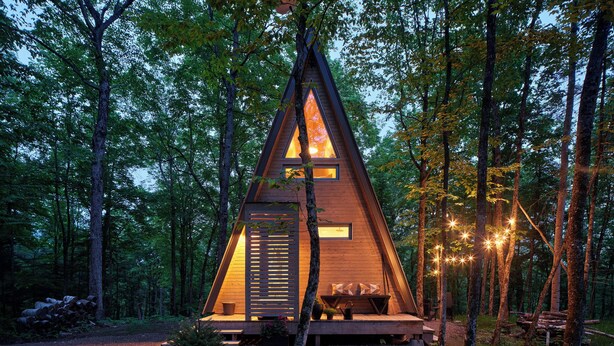 A wooden A-frame cabin with a porch, surrounded by trees. - Prunella № 3, Prunella № 3 - A-Frame Cabin Getaway - Design, Comfort & Nature (Thorne)