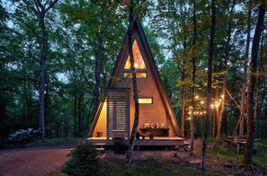 A wooden A-frame cabin with a porch, surrounded by trees. - Prunella № 3, Prunella № 3 - A-Frame Cabin Getaway - Design, Comfort & Nature (Thorne)